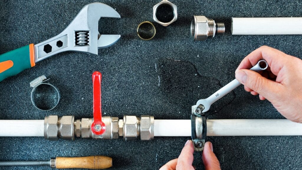 Plumber repairing a pipe valve with an adjustable wrench in Commerce City