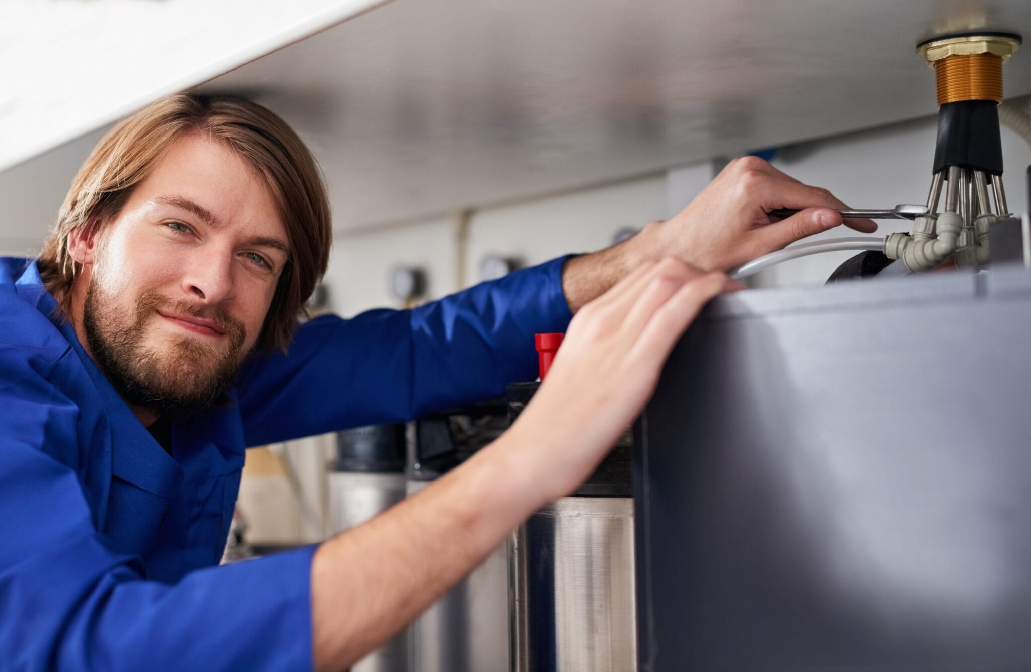 Technician servicing a residential water heater tank in Commerce City